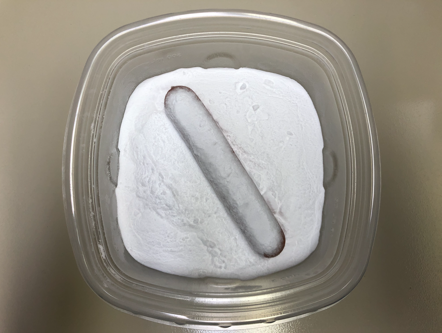 a hot dog sits in the middle of a plastic container covered in baking soda